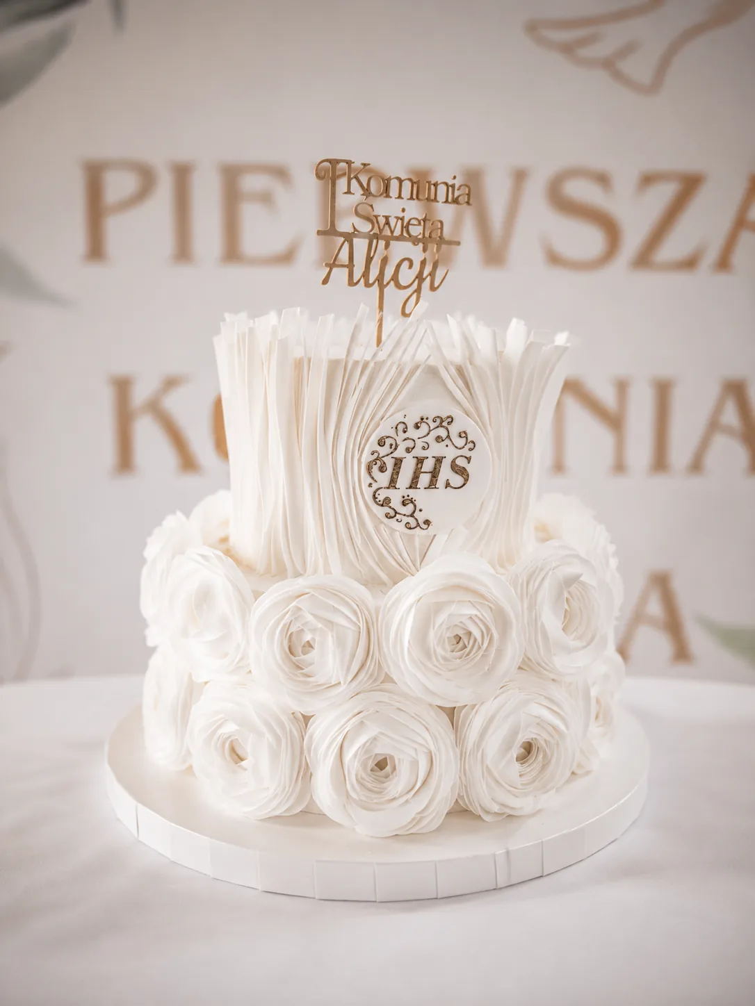 Biały tort komunijny z dekoracją z róż przygotowany na przyjęcie w Fantazja.