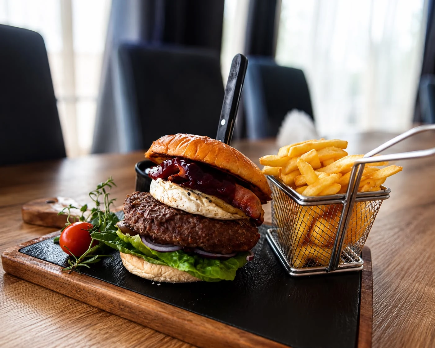 Burger wołowy z frytkami i dodatkami podany na desce w Restauracji Fantazja.